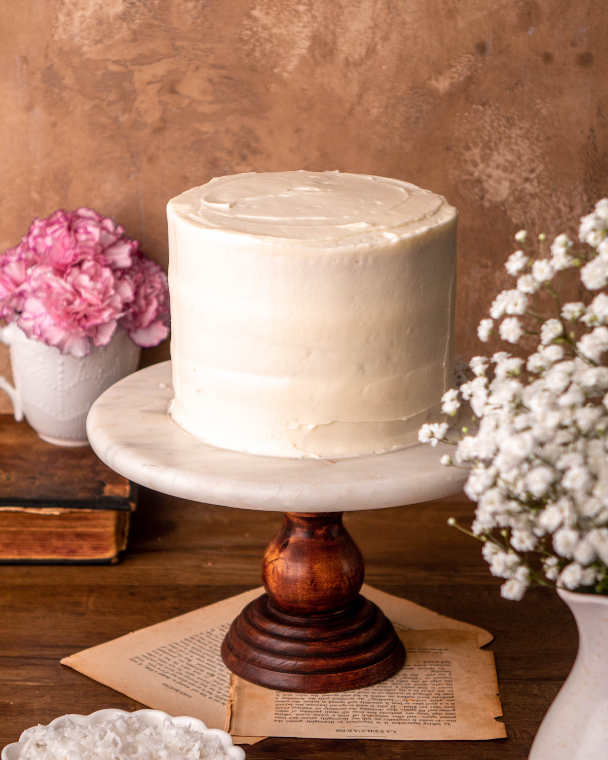 cake frosted with cream cheese frosting on a marble cake stand 