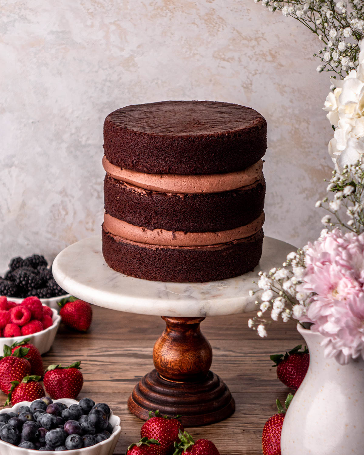 three cake layers stacked with chocolate buttercream borders and jam filling