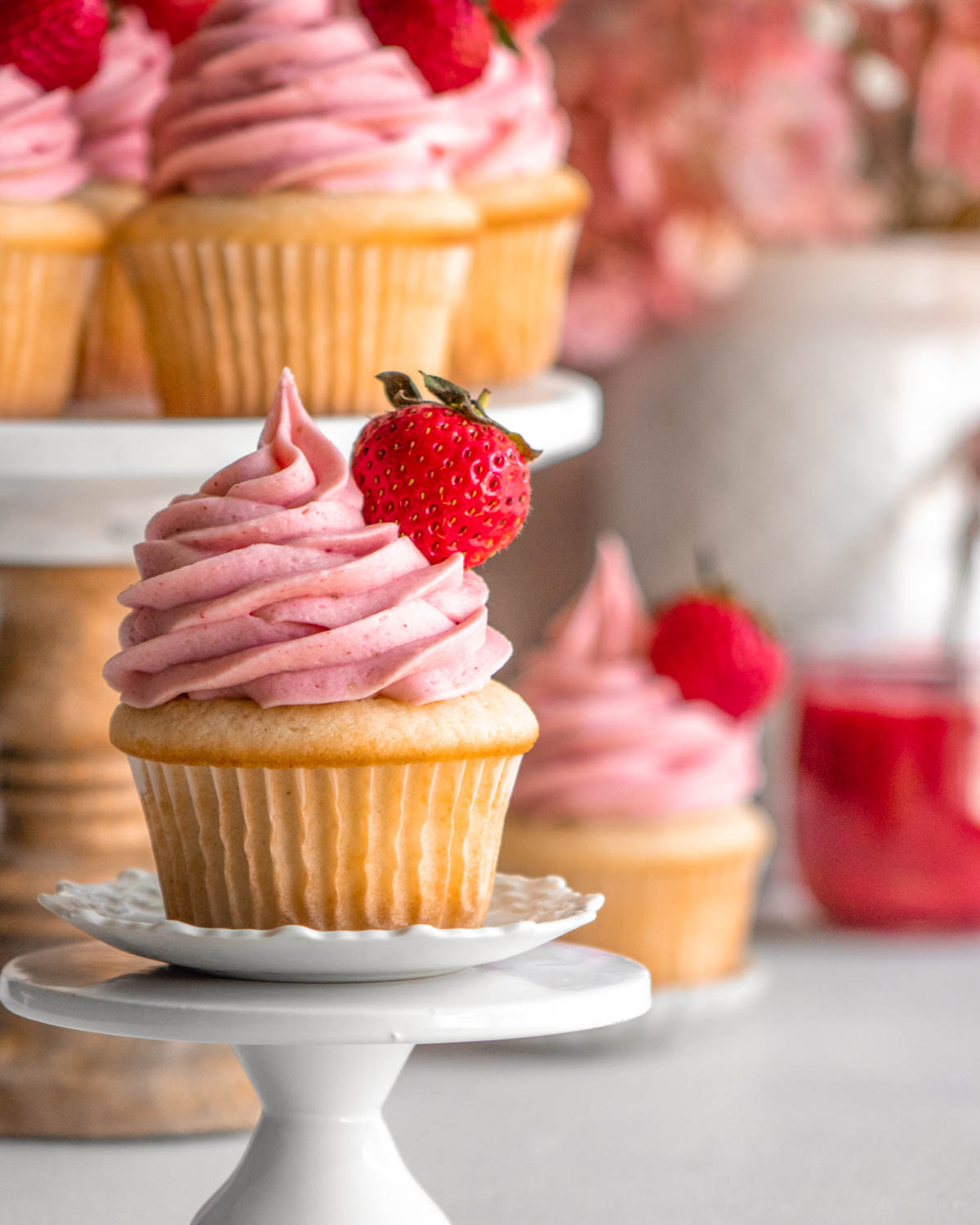 strawberry cupcake on a cupcake stand with other cupcakes in the background 