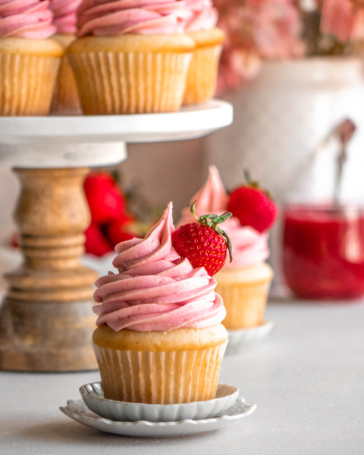 strawberry cupcake on a little plate with other cupcakes in the background 