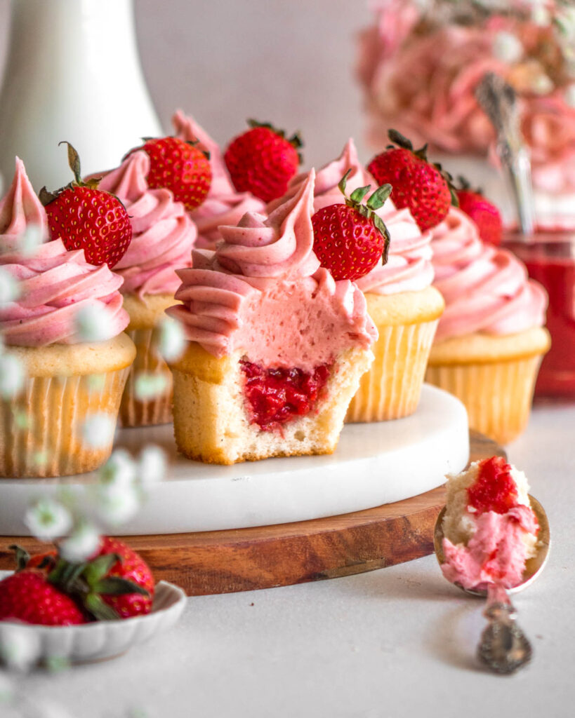 strawberry cupcakes on a marble tray, one with a bite taken out