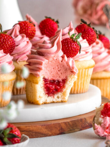 strawberry cupcakes on a marble tray, one with a bite taken out
