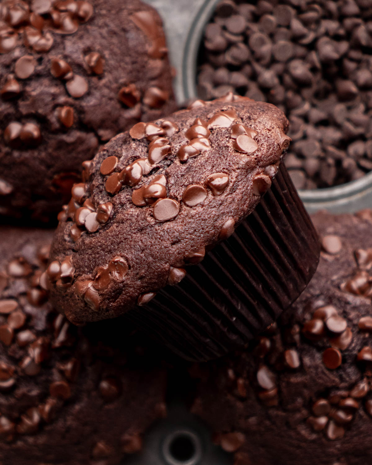 close up of chocolate muffin laying on other chocolate muffins