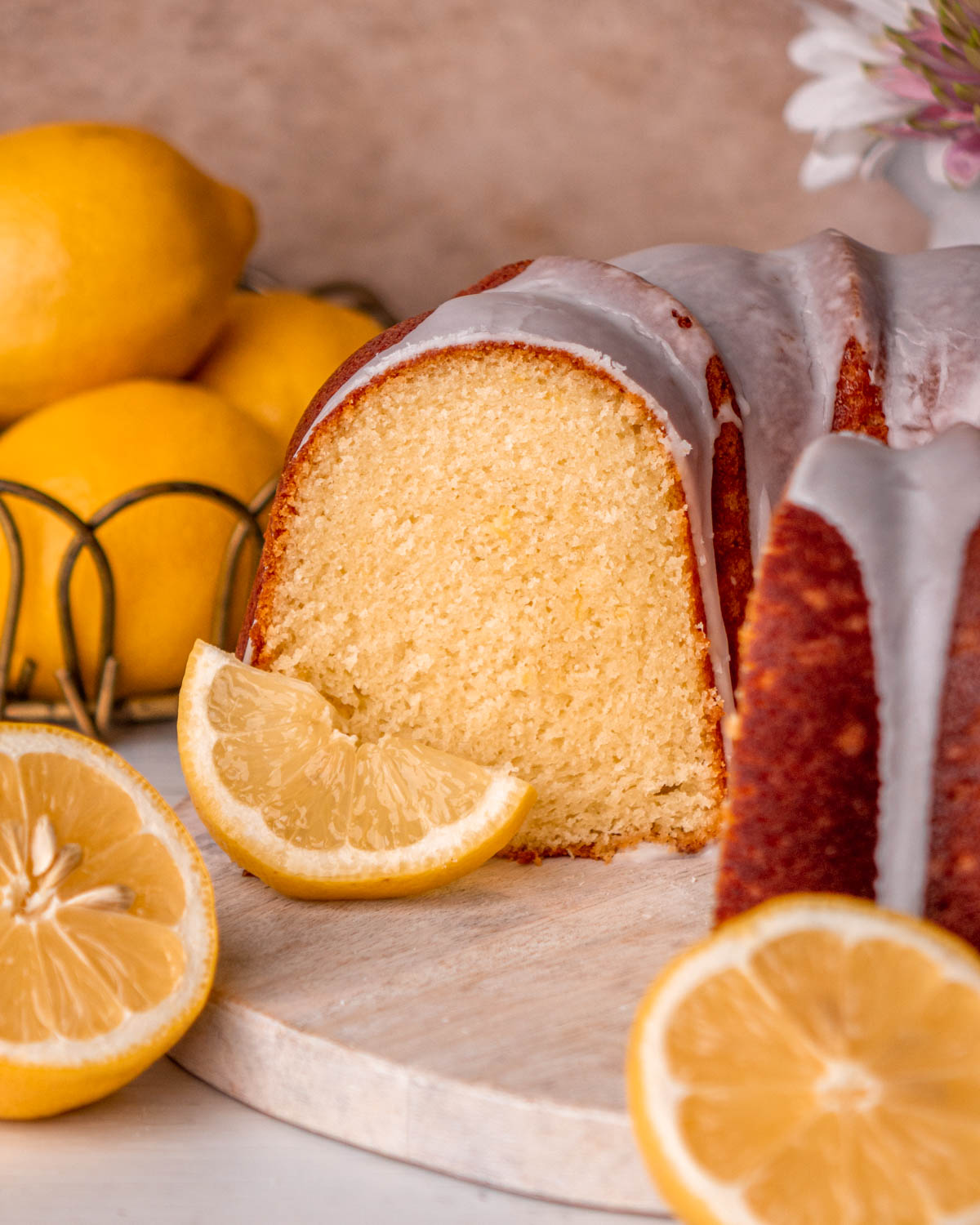 close up of cut open lemon bundt cake with lemons and lemon slice around