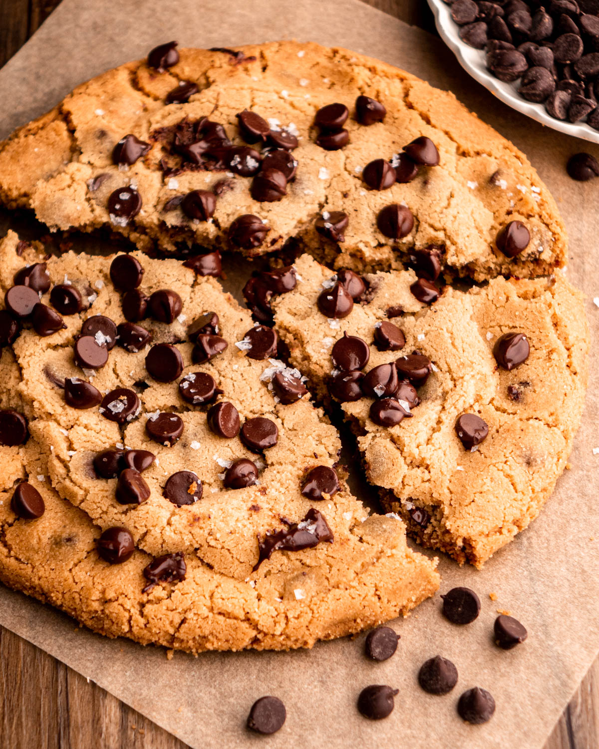 giant chocolate chip cookie broken apart on parchment paper