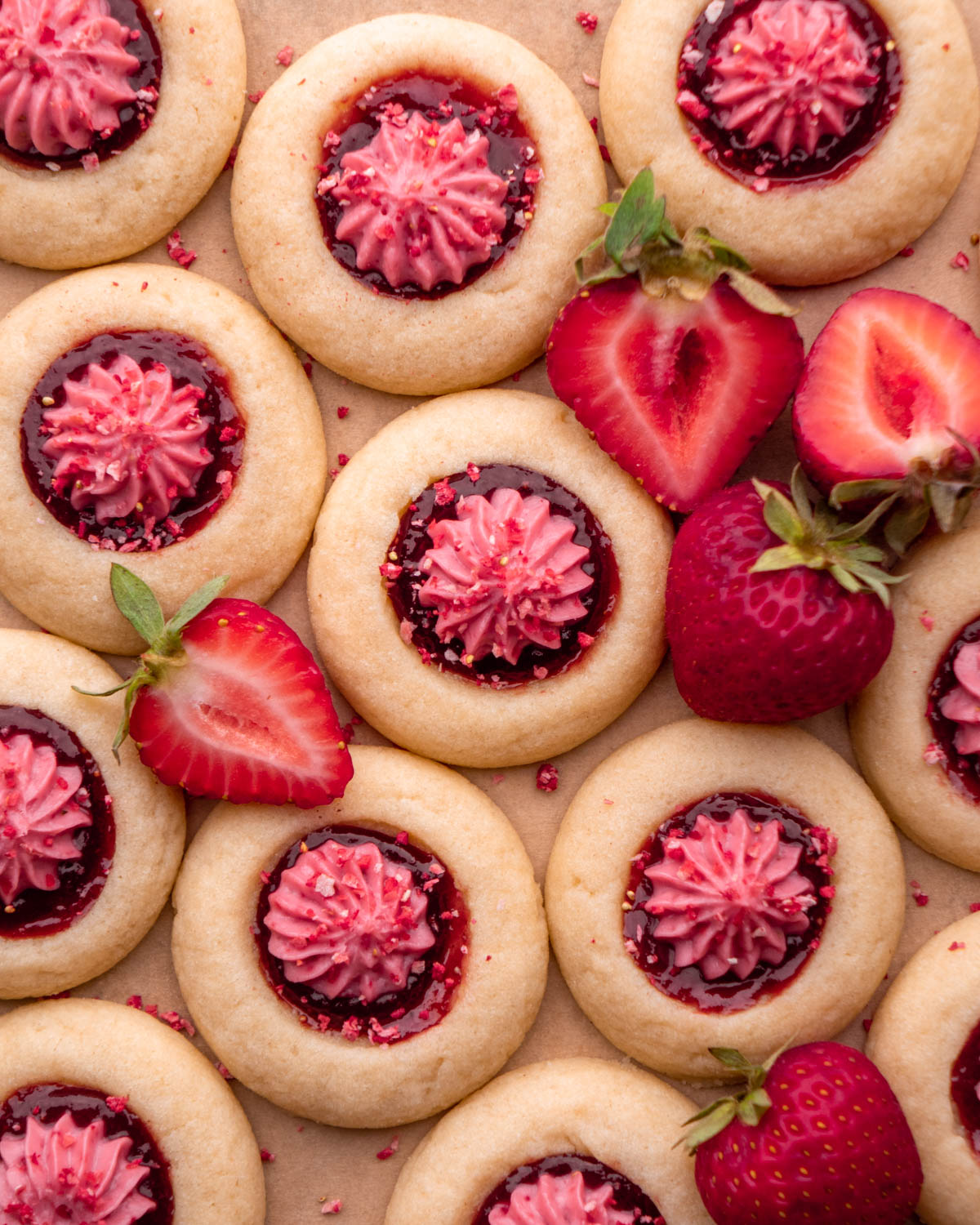 strawberry cheesecake cookies grouped together on parchment paper with strawberry slices around