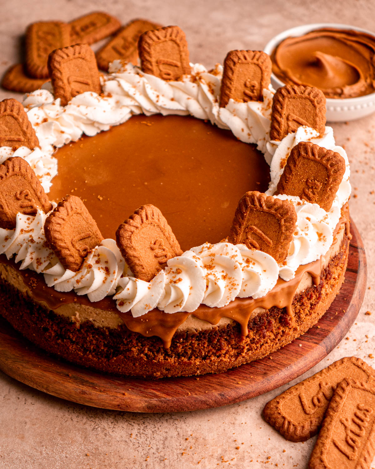 biscoff cheesecake on a wood board decorated with whipped cream and Biscoff cookies