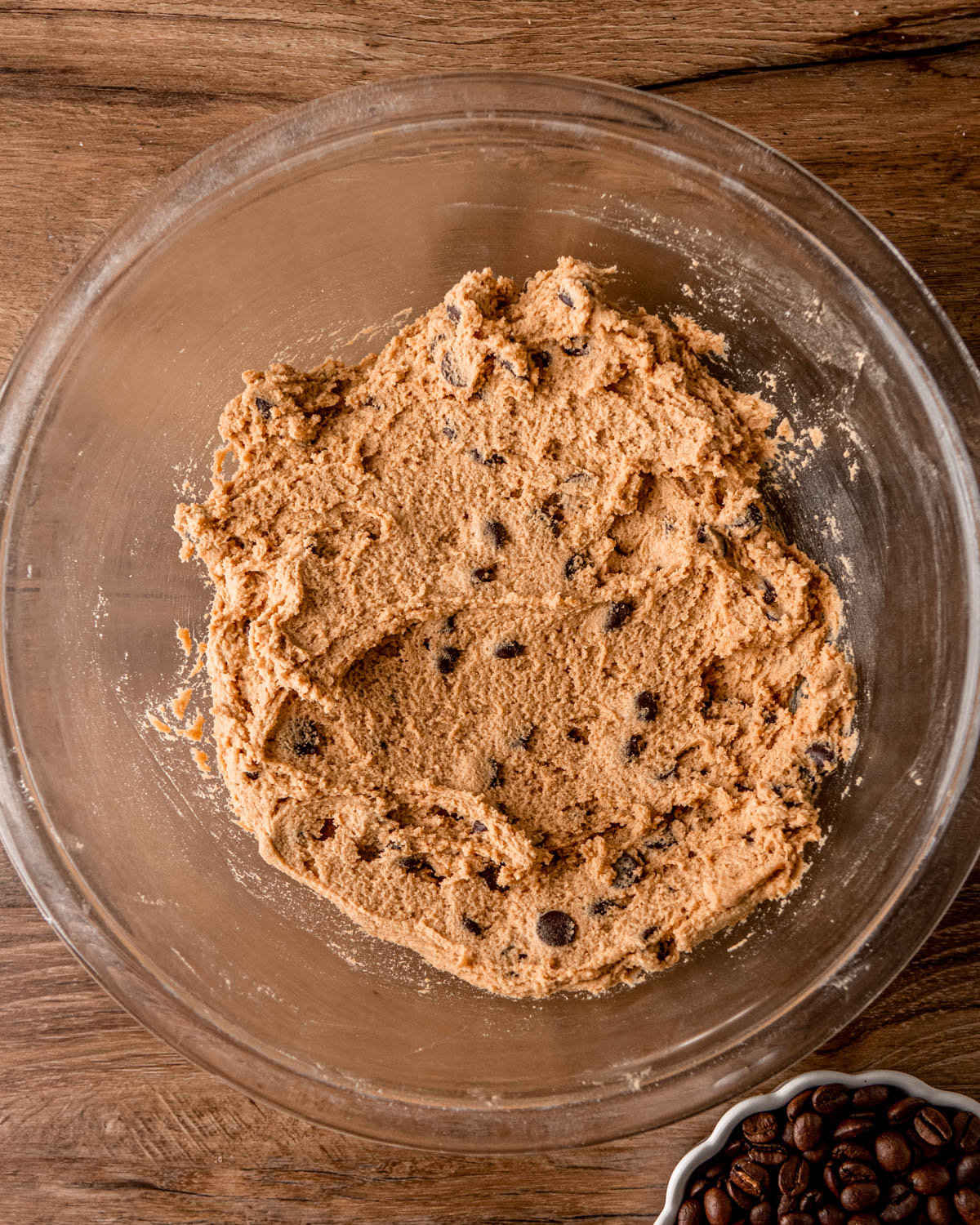 chocolate chips mixed into the cookie dough in a glass bowl on a wood board