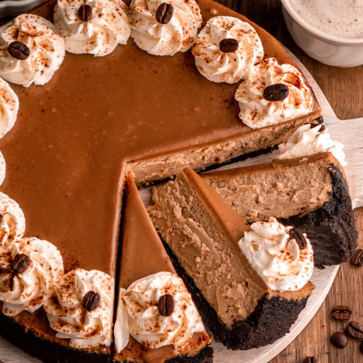 Coffee cheesecake with three slices laying on each other, on a white wooden serving plate