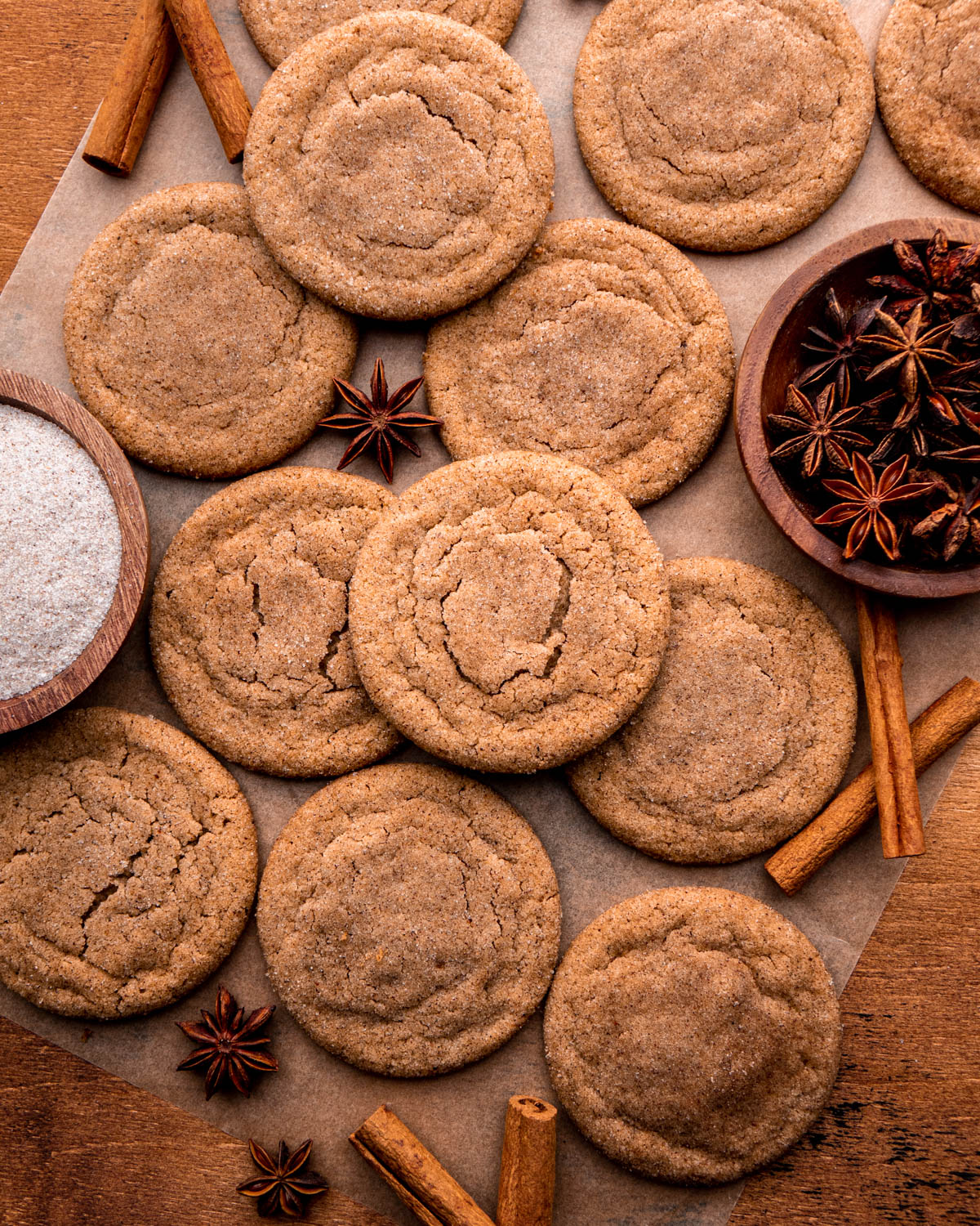 chai cookies arranged on parchment paper with star anise, spiced sugar and cinnamon sticks around