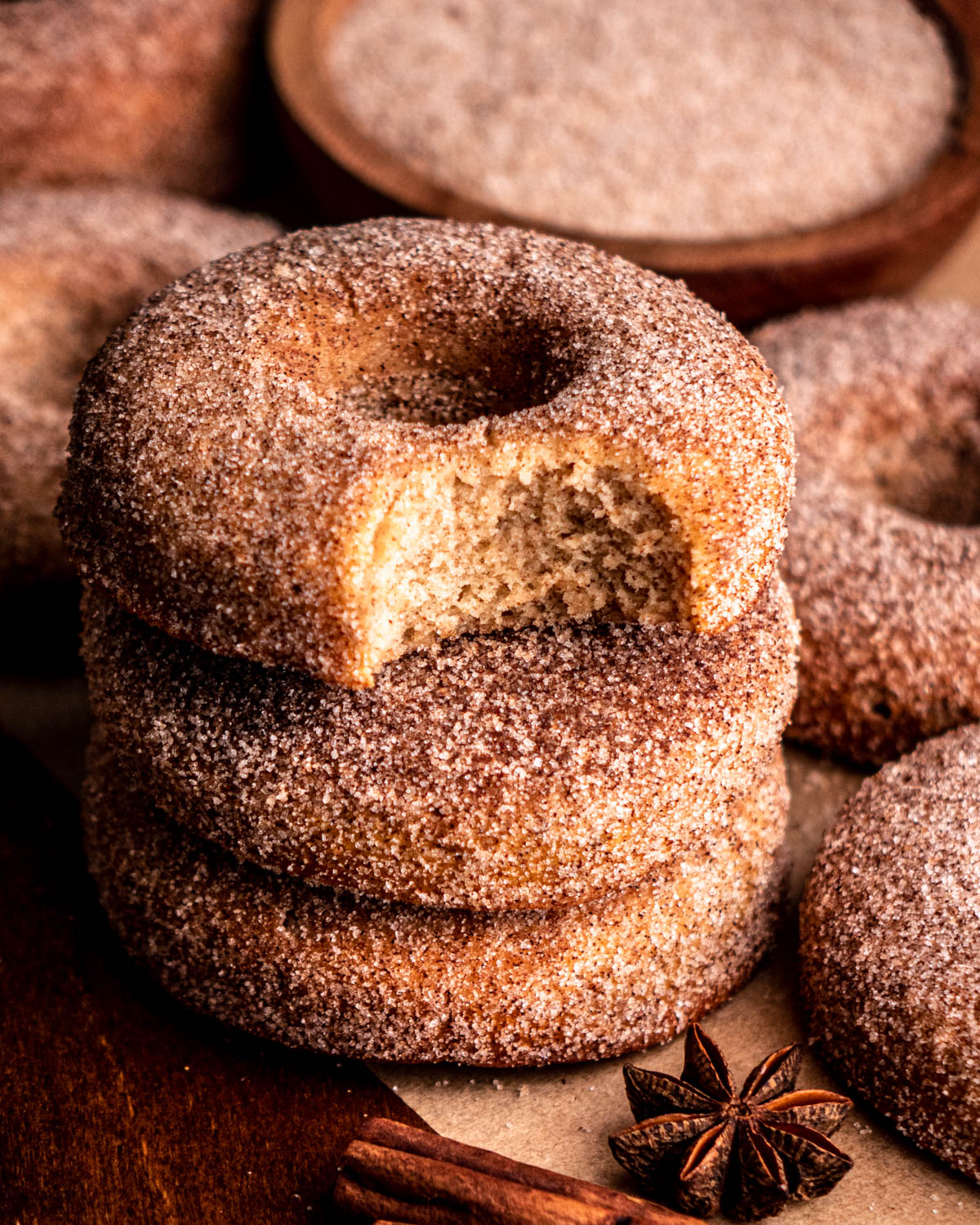 stack of cinnamon sugar donuts with a bite taken out of the top donut