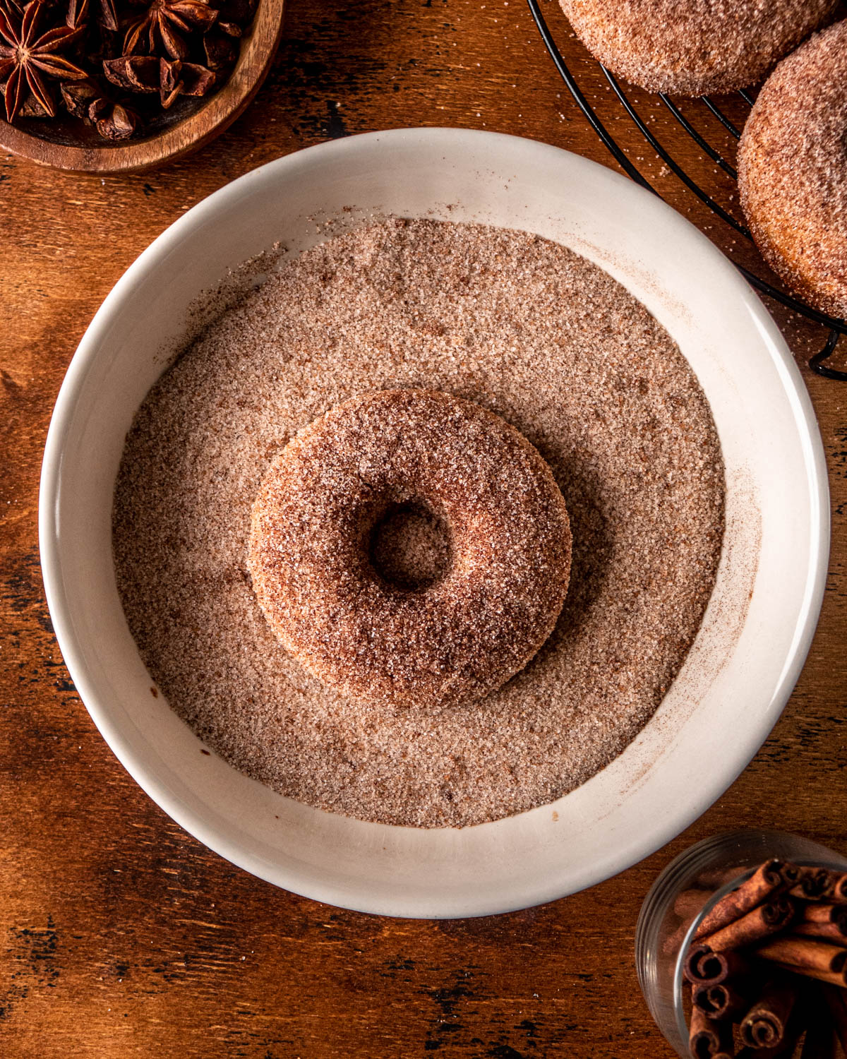 donut being covered in cinnamon sugar in a bowl