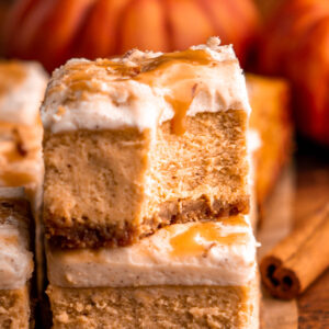 two pumpkin cheesecake bars stacked on each other, the top with a bite taken out