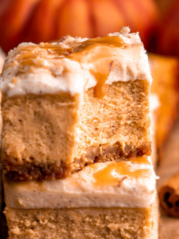 two pumpkin cheesecake bars stacked on each other, the top with a bite taken out