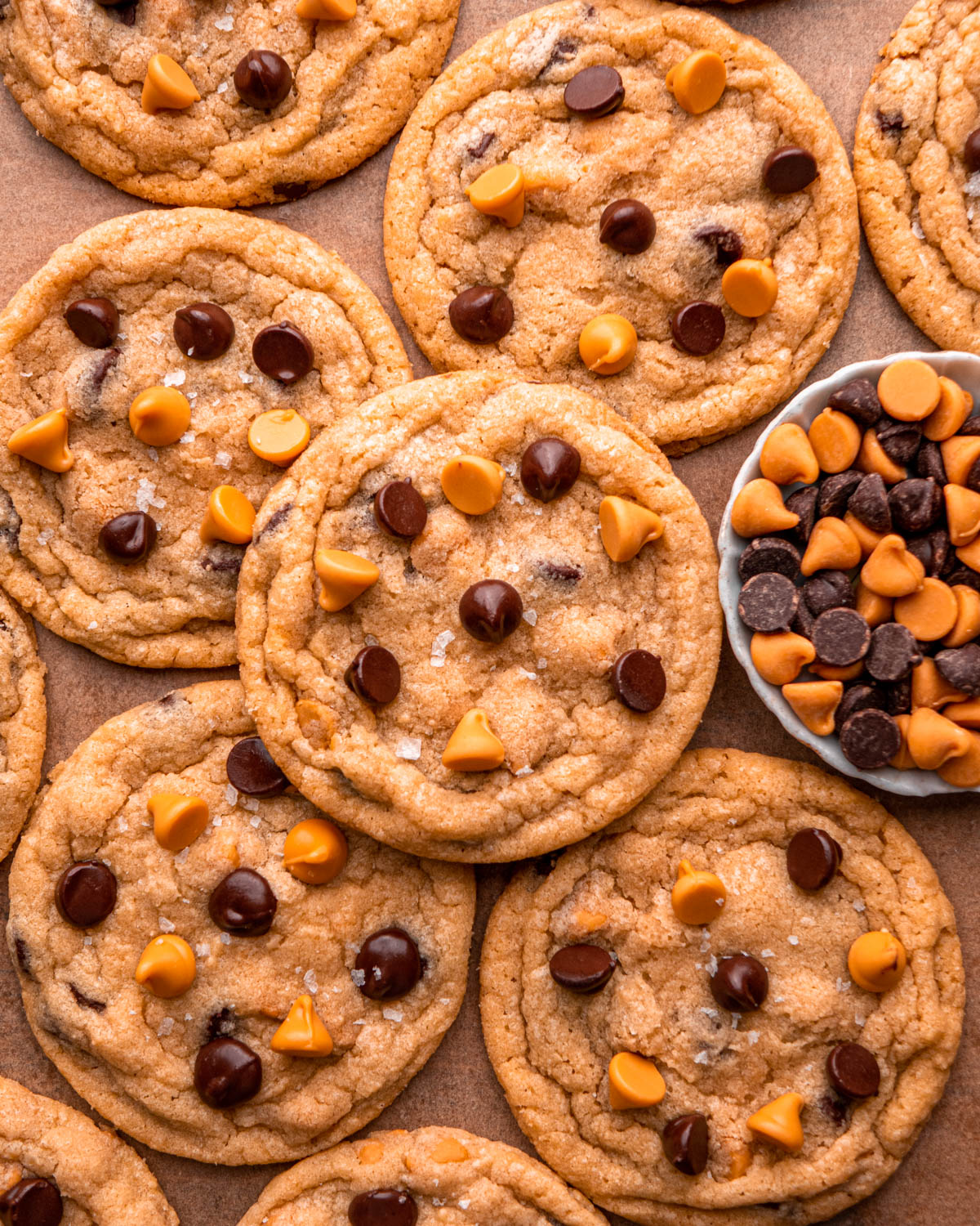 butterscotch chocolate chip cookies arranged around and on each other with a bowl of butterscotch chips and chocolate chips around