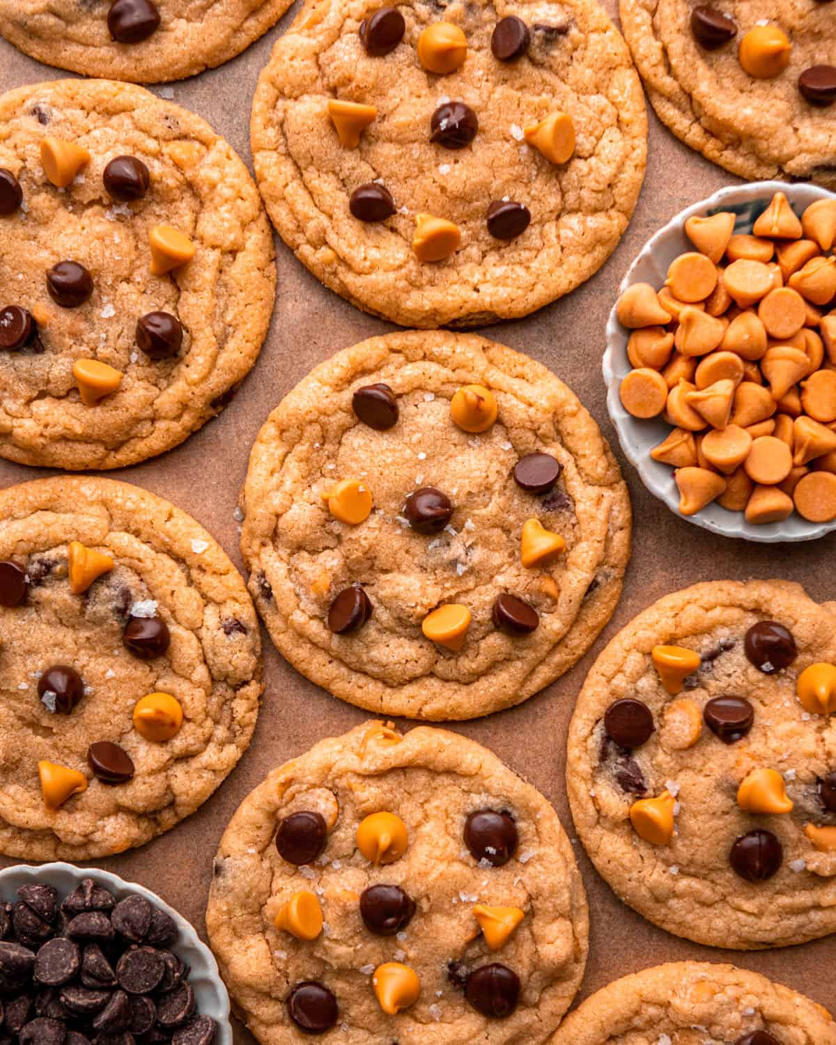 butterscotch chocolate chip cookies arranged around each other with a bowl of butterscotch chips and a bowl of chocolate chips around