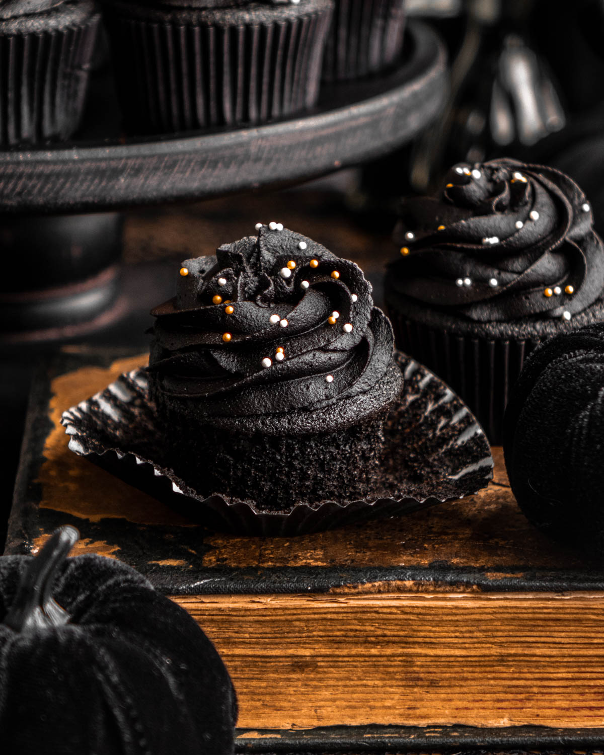 close up of a black velvet cupcake with the wrapper off on an old book
