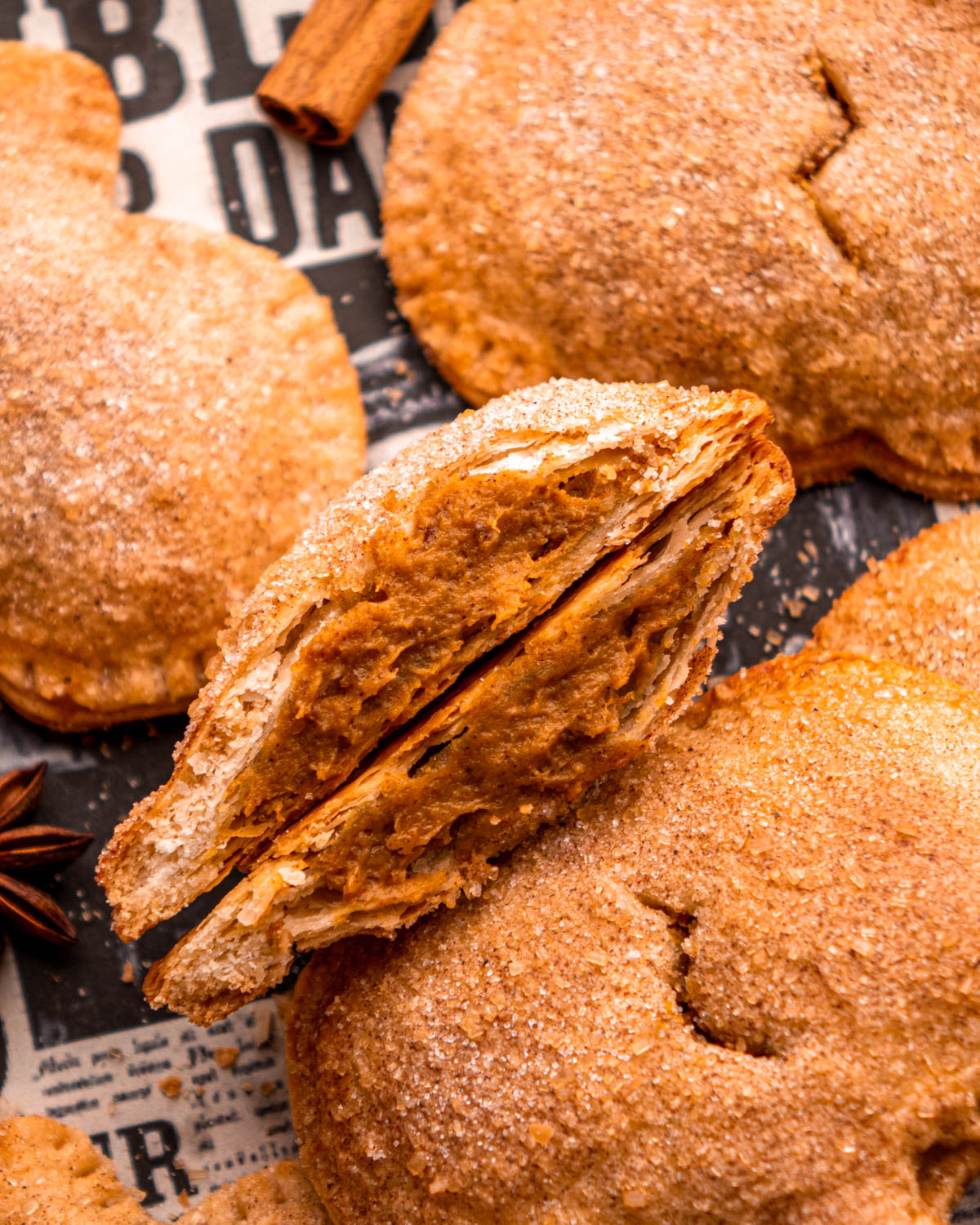 close up of pumpkin pasty cut in half so filling is visible, surrounded by other pumpkin pasties on newspaper 