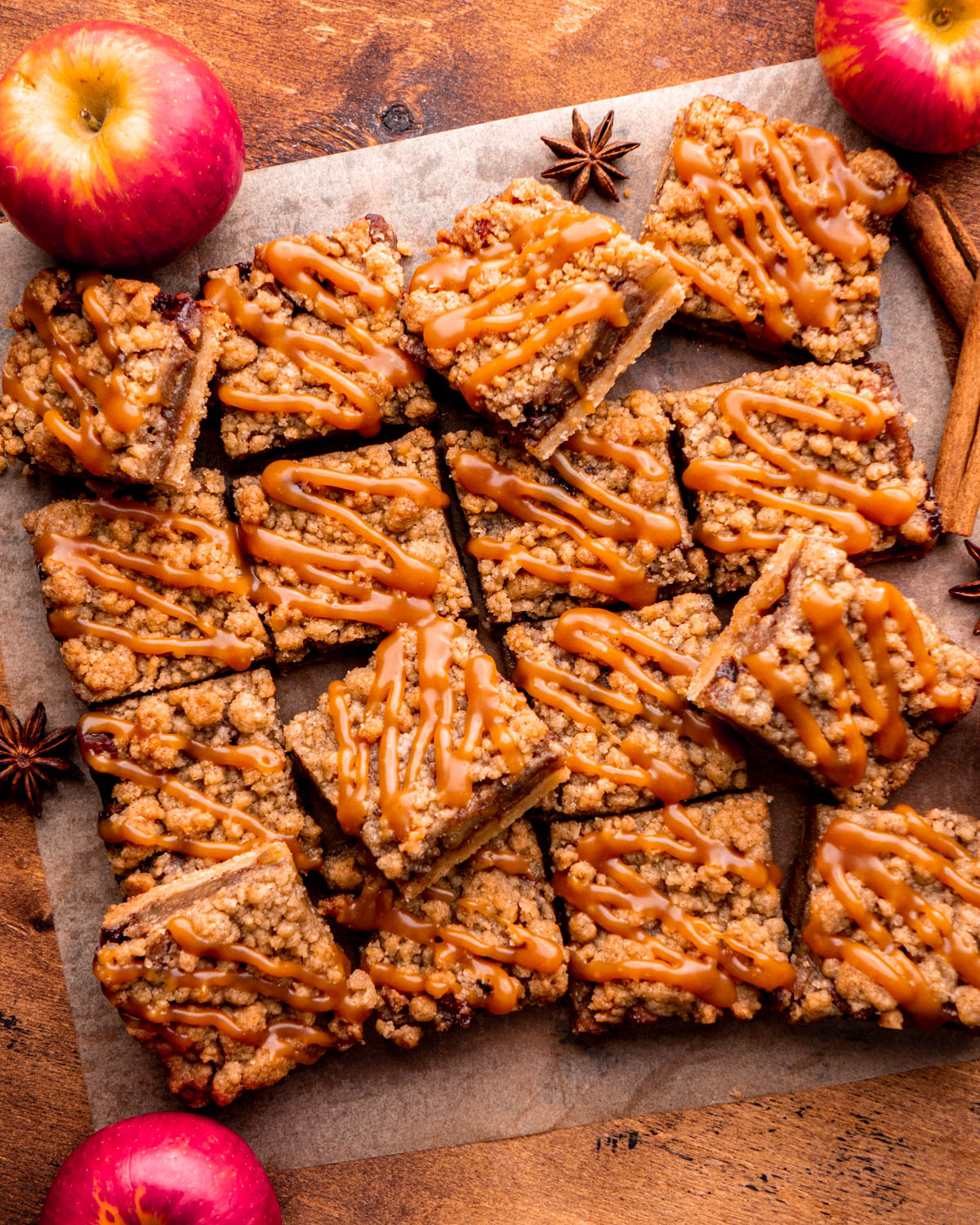 apple pie bars arranged on parchment paper with apples, cinnamon sticks and star anise around