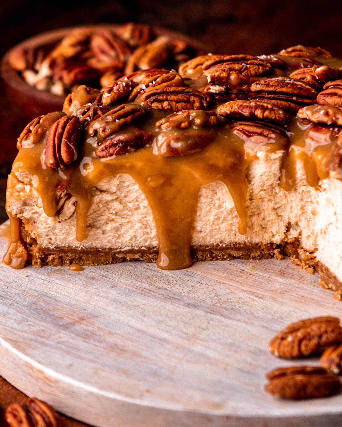 close up of cut open pecan pie cheesecake on a white wood board