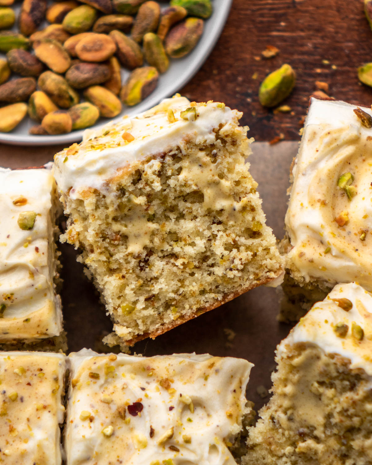 pistachio cake slice surrounded by other cake slices on parchment paper 