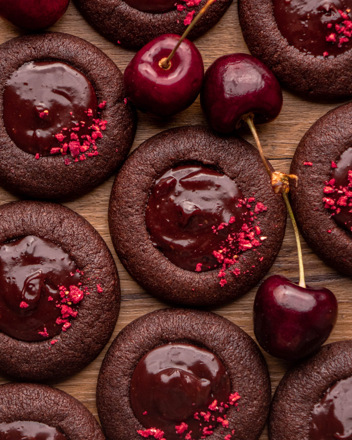 chocolate cherry cookies on a wood board with cherries around 