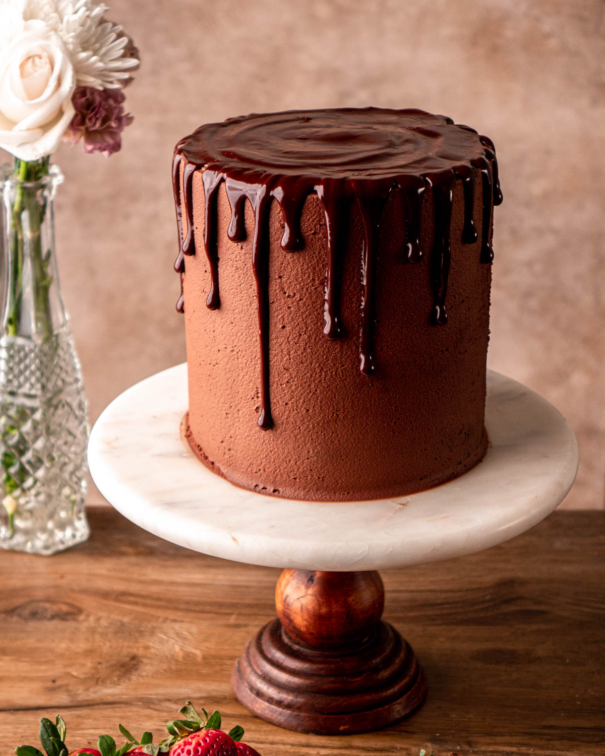 cake with ganache drip on, on a cake stand 
