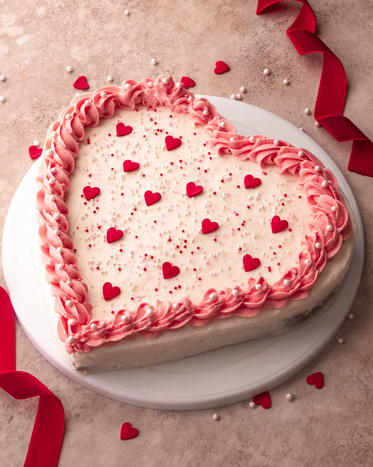 heart shaped cake decorated with pink icing and heart sprinkles