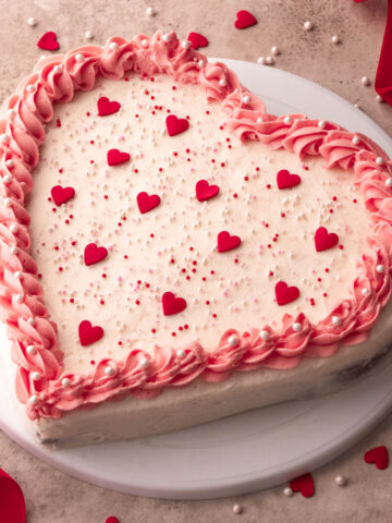 heart shaped cake decorated with pink icing and heart sprinkles
