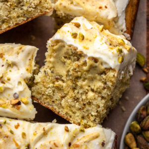 pistachio cake slice surrounded by other cake slices on parchment paper