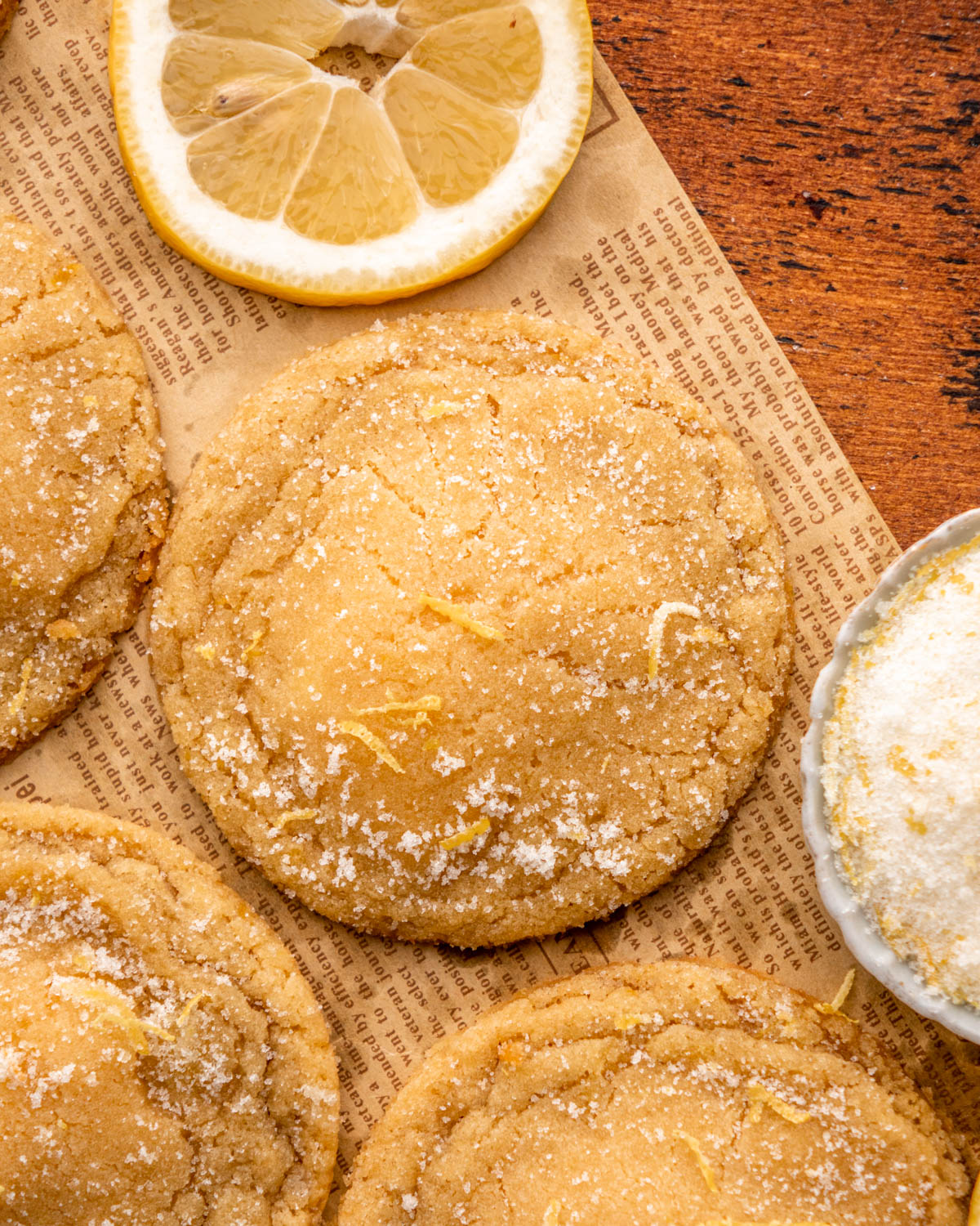 close up of lemon cheesecake cookie with other cookies and lemon around