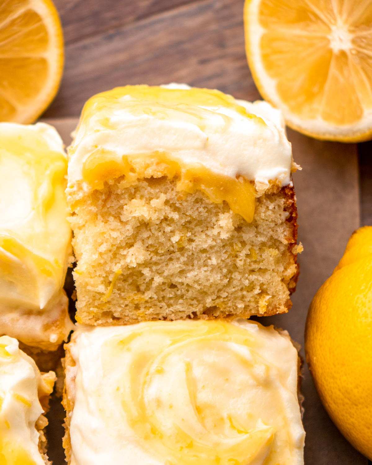 slice of lemon curd cake on its side with lemons around