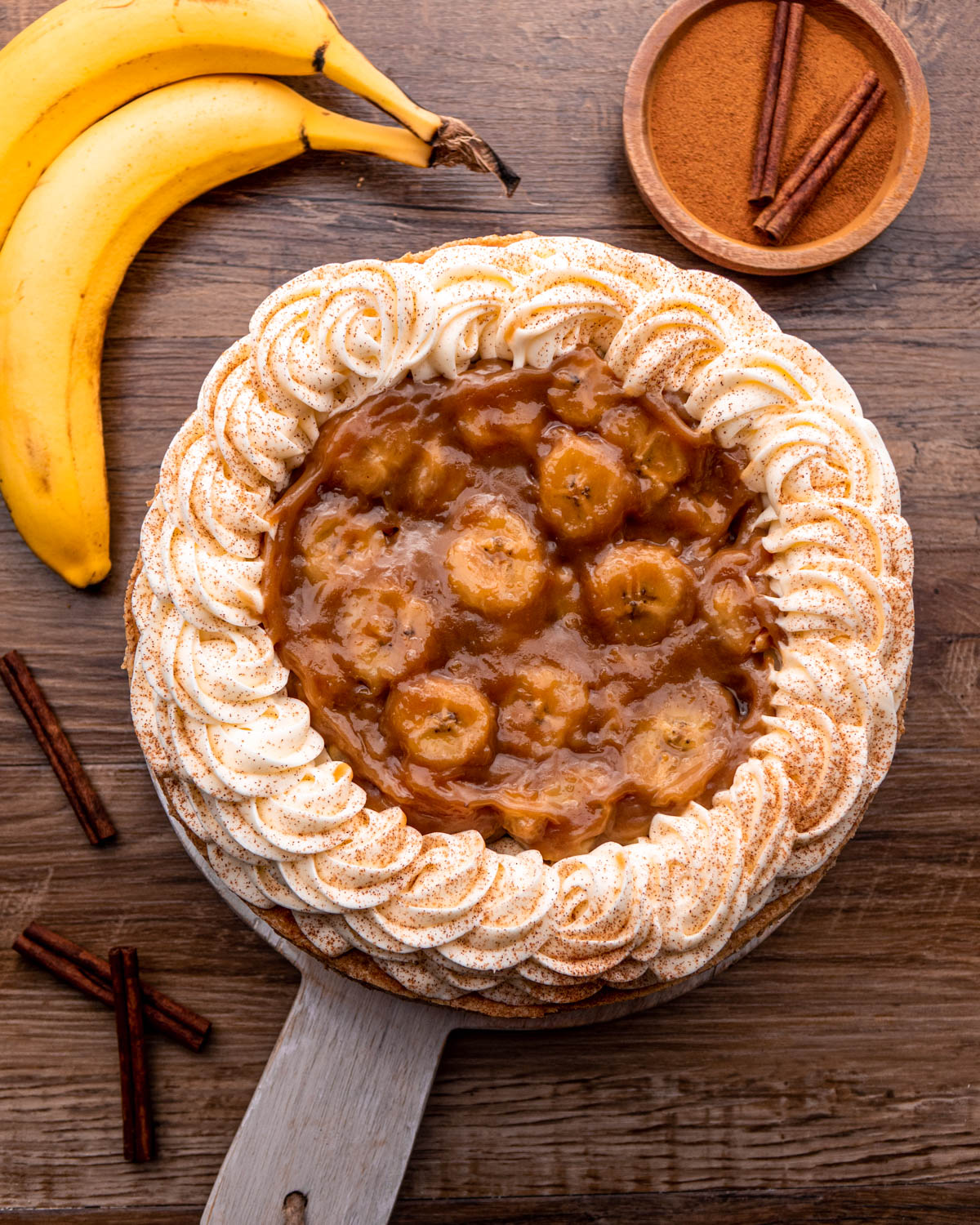 bananas foster cheesecake assembled on wood serving tray 